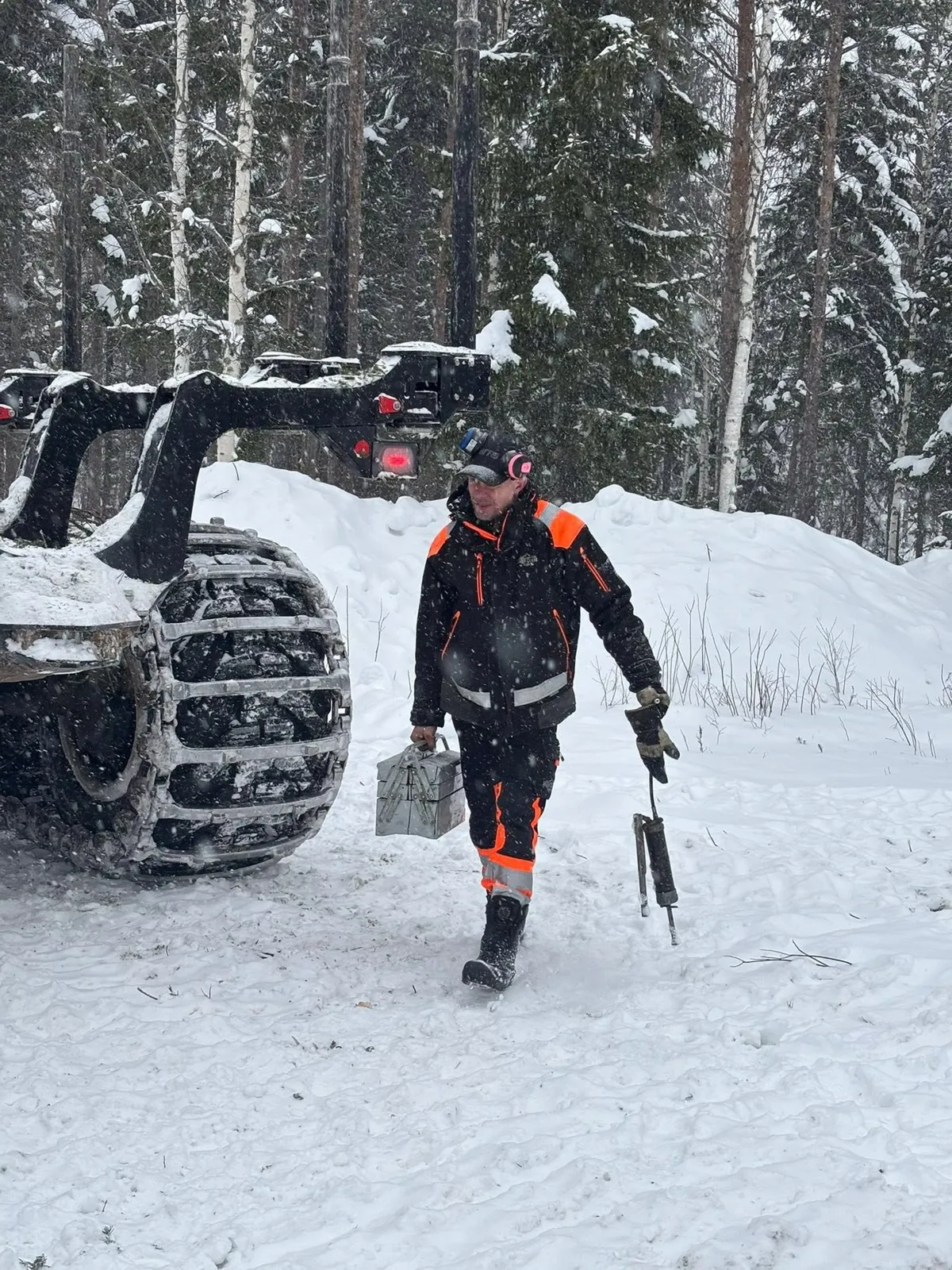 Förare går med verktygslåda genom snöig skog